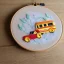 Placeholder: exquisite whimsical school bus in embroidery hoop, intricate, highly detailed, linen and wood backdrop