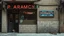 Placeholder: Facade of an old pharmacy with broken tiles and a faded neon sign. Urban pictorial realism, muted earthy palette, frontal composition. A sense of vivid memory and absence charged with presence. A cat dozes in the doorway.