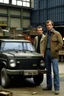 Placeholder: two haggard in their mid 30s looking men working in a land rover warehouse selling car parts to the public