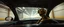 Placeholder: car driving happy insect man in the style of Escher and Giger and Fallout 4, pinhole cam, airbrush 3d rendering, on tv screen:A five-second cinematic single take in a clean industrial presentation hall.
