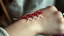 Placeholder: very close-up macro photo of a bracelet made of red, white, green lines yarn on a woman's wrist, detailed, sharp contrasts, realistic, cinematic, blur background