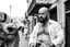 Placeholder: man looking like "Walter White" in breaking bad tv show, bald and goatee, with bare chest riding on a camel in a alley Casablanca town, panorama, black and white photo