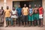 Placeholder: group of big stocky black mature muscular men from Niger , tank top, bulging shorts, inside a modest living room, queuing in front of the door of a room