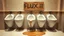 Placeholder: row of fine white porcelain urinals lined up on a wall in a nice restaurant men's room with marble floors and walls but one of the urinals is colored brown with a giant crack and is leaking brackish water on floor, above the broken urinal is a cardboard sign with written text "FLUX1.1", puddle of dirty water on floor, concept art, hyperreal