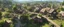Placeholder: A busy village market in beautiful surreal sunny countryside scene with distant hills, hedgerows, & fields. Many intricate dwellings, a clock-house, many raised pathways & stairways, walkways & bridges, waterfalls & a waterwheel : ultra high detail, photorealistic, epic cinematic, 8K, Large depth of field