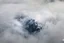 Placeholder: large scale, far away. a massive sheer snowy mountain cliff with very sparse vegetation scaling vertically into the sky, partially obscured by dense clouds(color d0d1d5) and mist. the borders — top, bottom, left, and right — fade smoothly into thick fog, while the center reveals the steep, far away rocky cliff face with fine texture and detail. atmospheric lighting, cinematic composition, natural colors, high contrast between fog and stone. photography