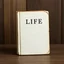 Placeholder: Un livre classique ancien blanc intitulé 'Life is'