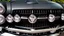 Placeholder: Photograph of a the front grill of a gorgeous, expensive, oldschool black muscle car with a big, black front grill, realistic, stylish, taken up close from the front of the car.