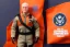 Placeholder: Mike pence G.i. Joe toy doll Space force uniform With accesories inside a blister packaging hanging on a Wallrack in toystore, fluorescent orange, toy guns, wide angle shot whole body, black moonboots, fullsize