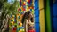 Placeholder: A robust Hispanic woman with wavy brown hair, wearing a colorful embroidered dress, exploring a vibrant forest of painted concrete cubes with open niches and windows, under a bright sunny sky in summer.