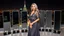 Placeholder: very beautiful model lady with makeup and beautiful modern fashion midi pleated velvet dark silver lace skirt with lace edges and modern loose lace top with a loose over, curvy silver long hair, standing in a modern city open satge with 8 cubic mirrors(each with 4 equal hight and equal width, vertical mirror), each vertical on its own short rotating base. with some small lights on crystal frames, on roof of a skyscraper with city escape at background, with animating dynamic lights with high