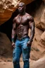 Placeholder: Alimi Ballard as very muscular male. bald with tribal tattoos wearing jeans and a teeshirt outside a cave