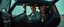 Placeholder: close up on weird out expression of guy suspended eating dogs inside laid back futuristic sci-fi glass human form car vampire coffin standing upright on wheels