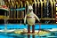 Placeholder: Dejected mottled lovecraftian anthropomorphic marshmallow man creature wearing a vintage 1920's vertical striped bathing suit holding a melting ice cream cone, surreal digital photograph, clear depth of field, in far distant background is a public swimming pool with someone floating face down in the middle, circular life preserver on a pole, surreal, dramatic, sinister, fantastical, complex contrast, dynamic