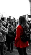 Placeholder: People going on strike with hand’s fest up and wearing masks all picture is in black and white style except a one beautiful girl in red is standing watching the crowd