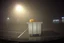 Placeholder: low-quality dashboard cam picture, high film grain, anthropomorphic fused centipede pumpkin hybrid hiding behind dumpster caught in headlights in a Wal-Mart parking lot in a foggy night, found footage horror, low contrast, night vision, static haze.