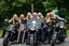Placeholder: a very hard and tuff motorcycle young gang with long blond Sweden viking hair, not old, posing with their Harley Davidsson bikes, some of them holding guns and shotguns, a logo sign with Falköpings HD Club, "Fearless sinners" Skulls and bones, skeletons and fire, Sweden vikings DEMONS, Swedish flags on bikes