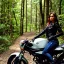 Placeholder: Very attractive woman sitting on a motorcycle. The bike is Yamaha. In the background is a forest.