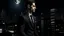 Placeholder: A man in a suit standing in front of a cityscape at night, with a full moon in the sky and tall buildings in the background