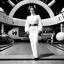 Placeholder: a standing revealing full body black and white photoshoot Princess Leia with her Star Puffs hairstyle, she is poised on hands and knees, by Helmut Newton, typical for the suggestive style of Newton (high quaintly perfect photo) the background is a space dock