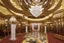 Placeholder: Inside an Art Deco Opera foyer, with mirrors and brass sconces, incandescent, gleaming, people in glittering extravagant costumes with feathers