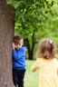 Placeholder: A small boy hiding behind a tree and a girl try to find him while playing hide and seek