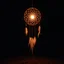 Placeholder: a dreamcatcher made of light, glowing internal light, natural red/brown tones, brown dirt ground long bottom, dark background