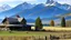 Placeholder: farmhouse and barn in foreground with rocky mountains in the background