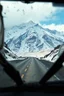 Placeholder: surreal mountain road seen through a dirty truck front window, dirty yellow snow and wind