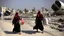 Placeholder: A Palestinian woman wearing a dress carrying very large bags of flour on her back, bending her back down in the destroyed Gaza City, and aid boxes descending from planes near the sea, with a large number of children looking up.