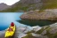 Placeholder: highly detailed glacial lake landscape, sunset, cinematic lighting, 4k, 8k, octane render, popular on 500px, pinterest, extremely detailed, ambient lighting, single frame, small fiberglass yellow solo narrow symmetrical sea kayak on rock pebble beach in foreground, norway, iceland, fjord