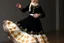 Placeholder: Long shot of an Azeri woman dancing in a traditional “Arkhalig” velvet jacket and a long, flowing “Tuman” skirt embroidered with gold “Buta” patterns. She wears a “Gümüş Kemer” (silver belt) and a “Ruband” silk headscarf held by a gold “Tiara.” Her hands are performing “Şana” (comb-like) finger movements. She spins slowly, the heavy fabric of her dress billowing outward in a controlled, elegant circle.