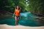 Placeholder: beautiful girl in blue short and orange top walking in water toward camera in trees next to wavy river with clear water and nice sands in floor.camera capture from her full body front