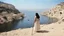 Placeholder: [photo by Russ Meyer] close to the old town of Nazareth, a view on the Lake of Genesareth. a young woman in linen dress, she has her wooden rod she looks at the people down around the shore