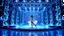 Placeholder: a 3d fractal stage structre made of metallic blue theme 3d structures, pertty artistc background,dynamic lights,lady prances in modern fashion clothing dansing in stage