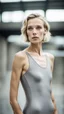 Placeholder: beautiful anorexic woman, total shot, short grey metallic triathlon swimsuit, short blond wavy bob hair, blurred concrete background