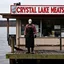 Placeholder: horror movie still, grainy color photography, faded colors, nihilistic, text "CRYSTAL LAKE MEATS" sign on a dilapidated butcher shop on a pier of a lake, foreboding, Jason Vorhees wearing a hockey mask and a butcher's apron standing in shop window, dramatic