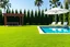 Placeholder: 4k Image is a digital rendering of a spacious backyard garden, featuring a lush green lawn that stretches across the foreground. On the right side, there is a rectangular swimming pool with clear blue water, surrounded by six white lounge chairs, each with a white cushion. A large white umbrella provides shade over one of the chairs. To the left, a wooden pergola with a slatted roof stands over a dining area, which includes a long table and several chairs. The background is filled with tall, den