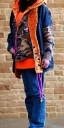 Placeholder: Brunette woman. average body type, think thighs and thick calves. Mantle is sewed of recycled Denim and sewed together of camouflage pieces. Printed camouflage figures are orange,terracotta, cream and purple. It is with big bright purple felt tippet and cream-colored-hood. mantle is merged with satchel. . AKG-style headphones (gold rings!) is merged with small felt cap with small visor. Style: Haute Couture in 1936, Paris fashion in 2023, inspired by street art. Cream latex gaiter.