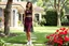 Placeholder: very beautiful lady with beautiful midi dark black-red lace skirt and lace top with curvy hair sports shoes standing in a nice villa yard with trees flowers ,16 by 9
