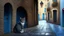 Placeholder: A cobbled alleyway, framed by stone arches, was almost empty save for a cat that slowly crossed, indifferent to the rain. In one corner, a woman in a blue coat waited under a black umbrella, her boots sinking slightly in the accumulated water.