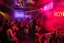 Placeholder: dans golv på en nedsliten sunkig techno club, många personer som dansar, yppiga kvinnor, mycket scen rök i lokalen, och gula röda strobes, en del personer ser in i kameran och skriker: "Benny!" och en Neon Skylt med texten "DJ ROY" på väggen, DJ Roy skriker rätt in i kameran, öppen mun, mycket flaskor och glas i baren