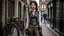 Placeholder: full-height portrait of a woman with straight shoulder-length black hair, with metal arms and legs, dressed in leather trousers, and a waistcoat, in a Victorian street next to a steampunk bike