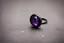 Placeholder: небольшое чёрное кольцо с лиловым камнем на нем выпало на пол.
