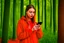 Placeholder: young woman in red clothing standing in a forest holding a smartphone