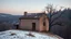 Placeholder: a lonely old adobe hut with worn adobe brown-gray wall and a small window, a crumbling roof, an old chimney stands on a hill, next to it is a small woodshed by the wall, and an old withered tree leans over the hut, the hut stands on the edge of a European forest, winter, snowy landscape, low light, dawn, high detailed, sharp focus, high realistic, perfect photo