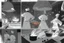 Placeholder: black and white storyboard, 3 chefs, scattered throughout the kitchen cooking, frying, cutting