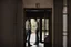 Placeholder: man in jeans and a shirt, back to the camera, standing in a row of doors, looking out through a doorway