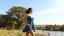 Placeholder: a beautiful lady in nice decolte mini dress sport shes in country side next to river and big tree,wild flowers standing