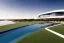 Placeholder: algarve in quinta do lago, one straight line building of 250 meters long pool of a modern luxury architecture with wood and gold metallic pergolas with pool on rooftop, on a slope with pinus pinea, a road wrap around for low speed veicular road